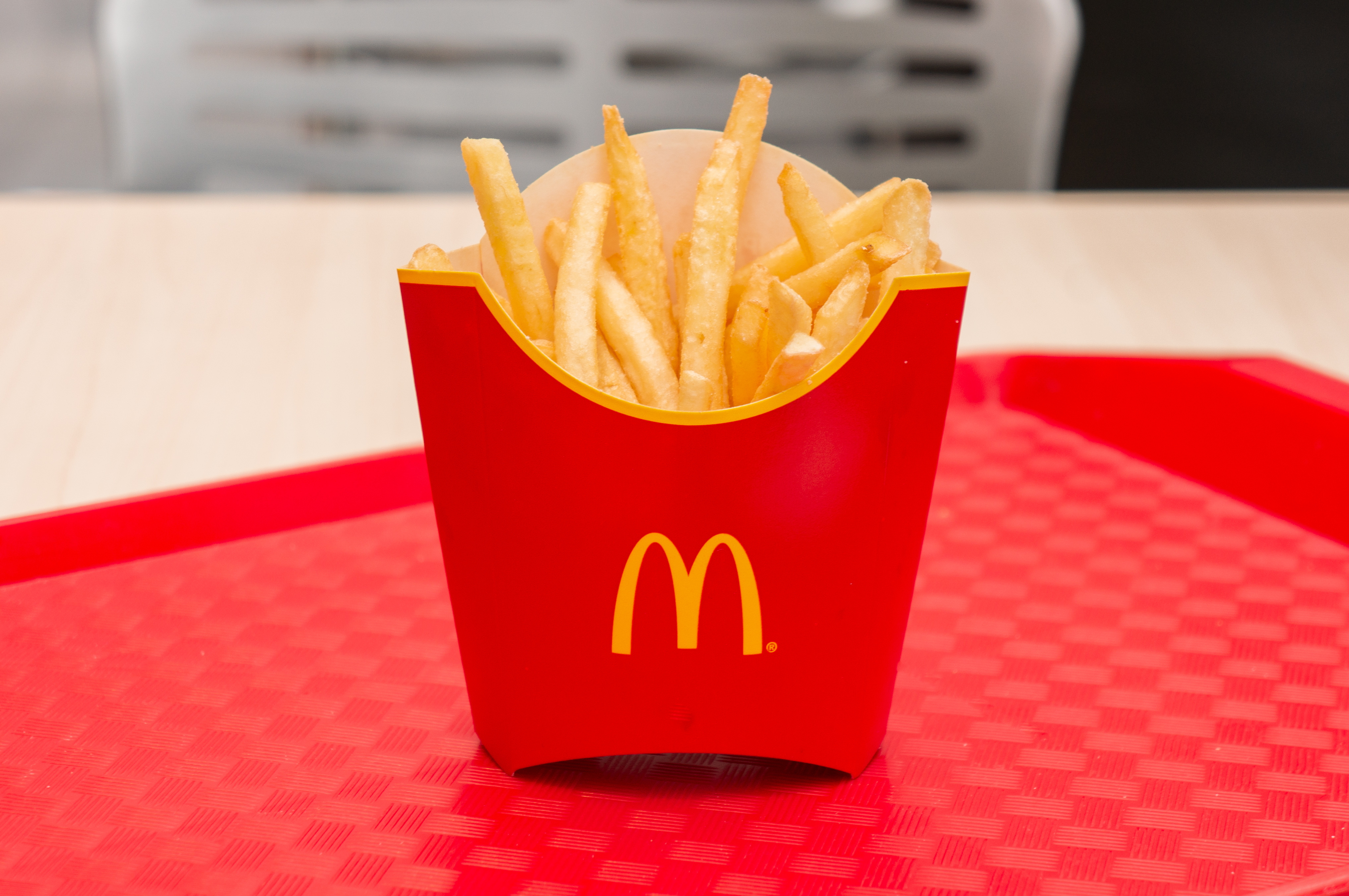 A red carboard basket of McDonald's fries on a red tray.