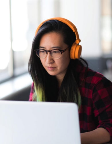 Young Asian woman wearing headphones on computer